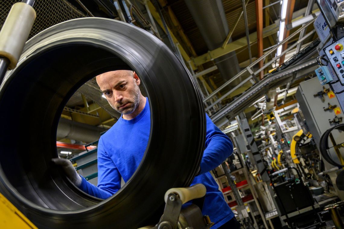 Un technicien contrôle visuellement la qualité d'un pneu dans une usine Michelin