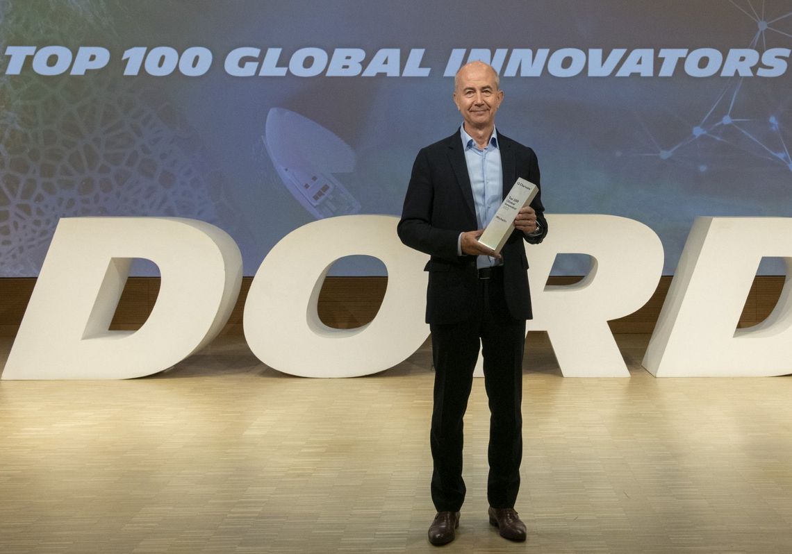 Éric-Philippe Vinesse tenant un trophée entre ses mains. En arrière-plan, une projection vidéo indique : "TOP 100 Global Innovators 2023 ". DORD (Direction Opérationnelle Recherche & Développement)
