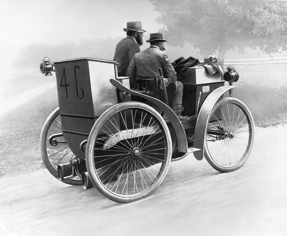 Black and white illustration showing André Michelin at the wheel of 'l'Eclair', a man is seated to his right, passenger side. The car has the number 46 on the rear.