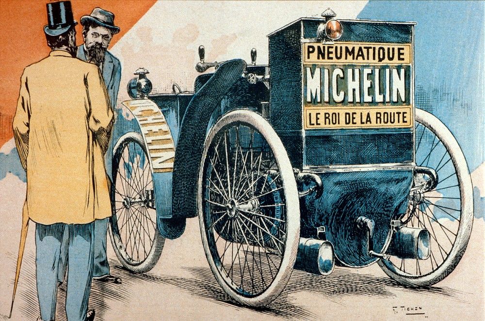 Color engraving representing ‘L’Eclair’. Affixed to the rear of the vehicle, a sign bears the inscriptions: ‘Michelin tires, the King of the Road’. Two men are on the left of the car, including Edouard Michelin. In the background of the illustration, the colors Red, White and Blue, emblematic of the French Republic, appear.