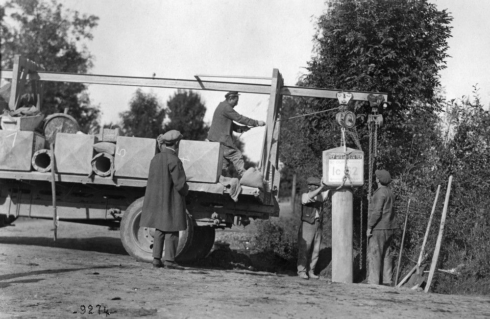 Photographie en noir et blanc montrant la mise en place d'une borne de signalisation au bord de la route.