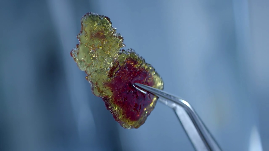 Zoom in on a crystallized ResiCare resin sample held by a clamp
